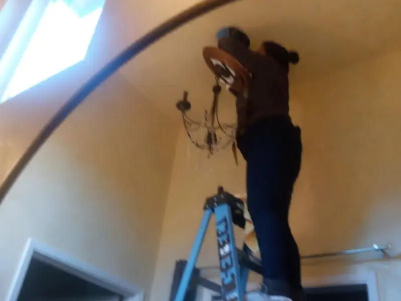 Electrician installing a chandelier in a Sherwood residence